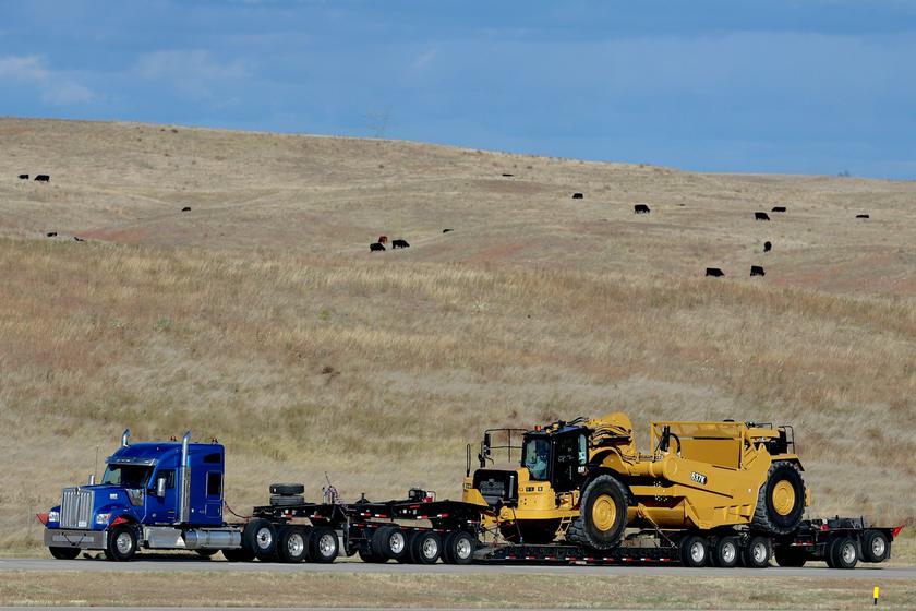 Blue semi truck hauling heavy equipment on a lowboy trailer