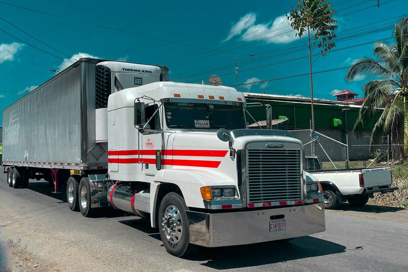 White semi truck with a refrigerated trailer and cooling unit